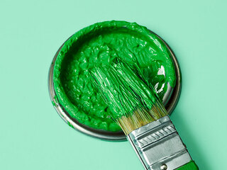 green paint in a paintbrush and lid of a paint can