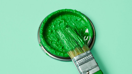 green paint in a paintbrush and lid of a paint can