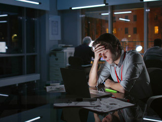 Portrait of exhausted stressed businessman work on laptop at night in dark office