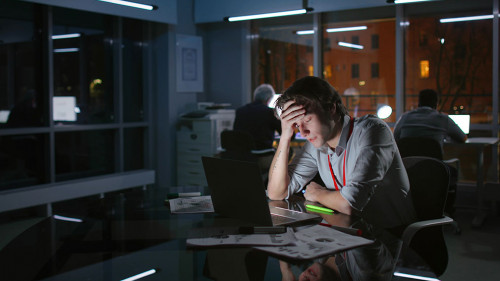 Portrait of exhausted stressed businessman work on laptop at night in dark office