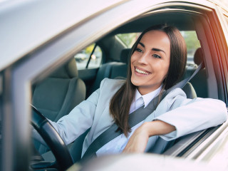Portrait of cute female driver steering car with safety belt