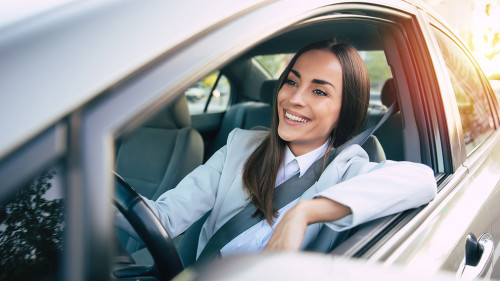 Portrait of cute female driver steering car with safety belt