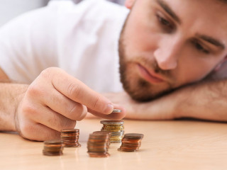 Sad young man counting money at home, closeup