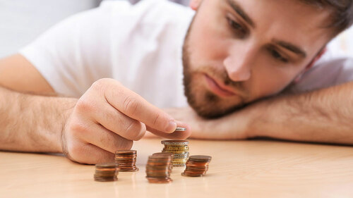 Sad young man counting money at home, closeup