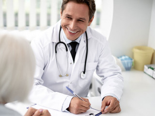 Waist up of cheerful practitioner smiling to the patient while working