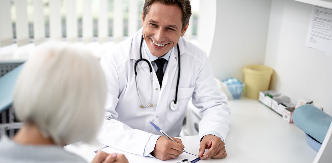 Waist up of cheerful practitioner smiling to the patient while working