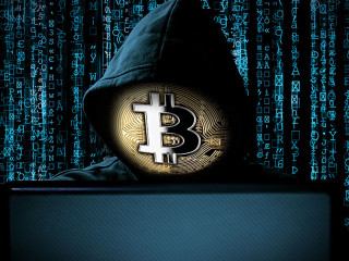 hacker with bitcoin face mask behind notebook laptop front of bl