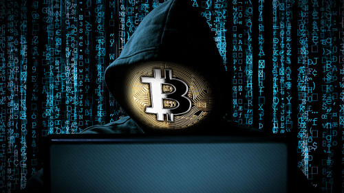 hacker with bitcoin face mask behind notebook laptop front of bl