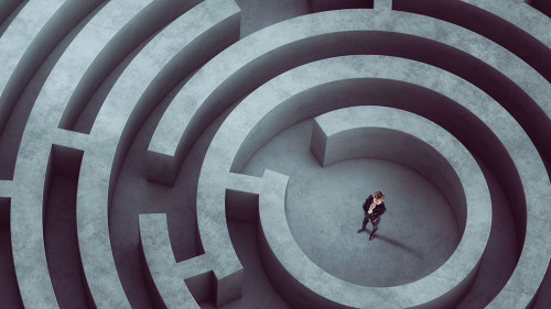 Confused businessman thinks how to find the right way to exit from a big maze