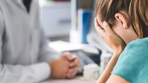 Sad patient visiting doctor. Young woman with stress or burnout