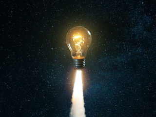 Creative burning light bulb rocket with blast and clouds of smok