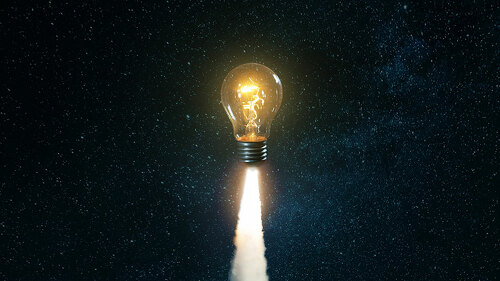 Creative burning light bulb rocket with blast and clouds of smok