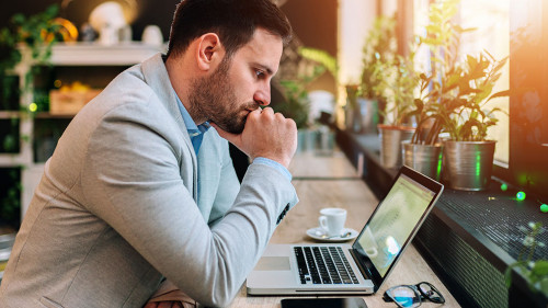 Thoughtful businessman looking at laptop screen