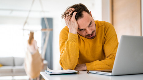 Frustrated young man working on laptop at home
