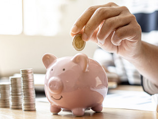 Woman putting a coin into a piggy bank in the shape of a pink pi