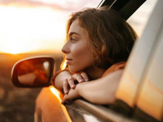 Happy woman outstretches her arms while sticking out the car win