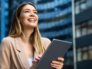 Portrait of a successful business woman using digital tablet in front of modern business building