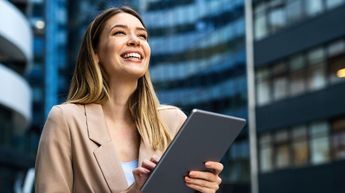 Portrait of a successful business woman using digital tablet in front of modern business building