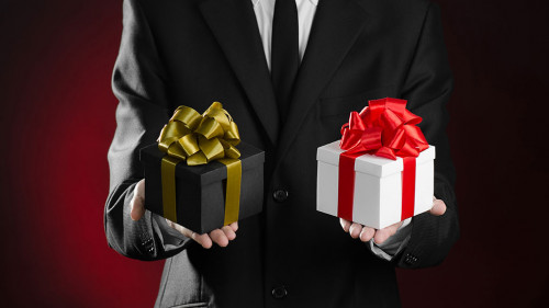 Theme holidays and gifts: a man in a black suit holding two excl