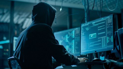 Shot from the Back to Hooded Hacker Breaking into Corporate Data