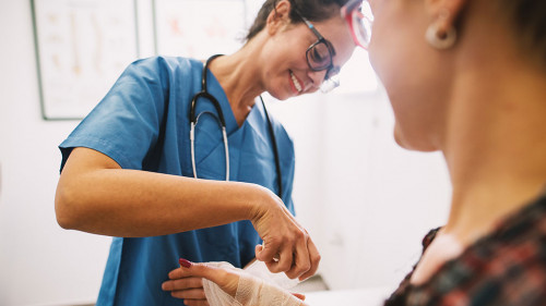 Professional nurse at the hospital bandaging the hand with a med