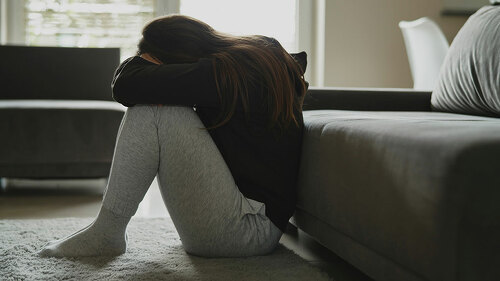 Caucasian broken woman sitting at the floor in living room