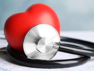 Stethoscope, red heart and cardiogram on table. Cardiology conce