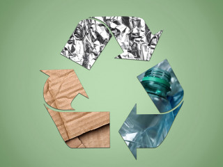 Recycling symbol made of crumpled foil, plastic bottles and card