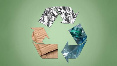 Recycling symbol made of crumpled foil, plastic bottles and card