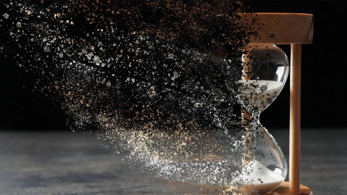 Time is running out. Hourglass vanishing on grey table against b