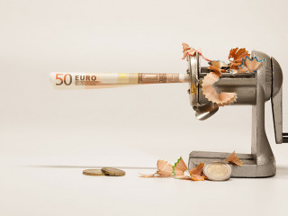 A twisted note in a sharpener with shavings symbolizes inflation