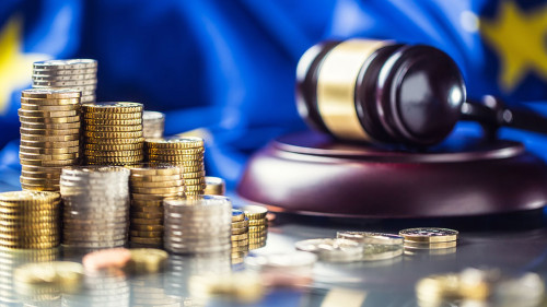 Towers with euro coins flag of European Union and justice hammer in the background