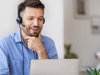 Business Education. Handsome businessman in headset watching webinar on laptop in office