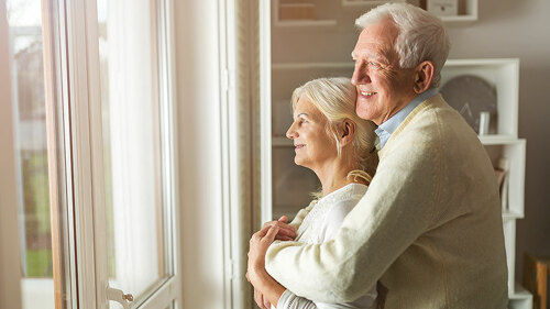 Senior couple looking out living room window