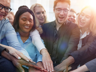 United coworkers standing with their hands together in modern of