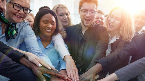 United coworkers standing with their hands together in modern of