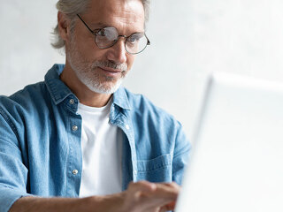 Middle-aged man working from home-office on laptop.