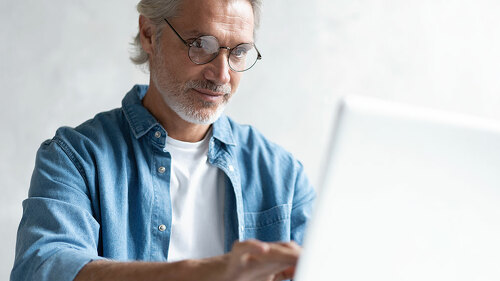 Middle-aged man working from home-office on laptop.