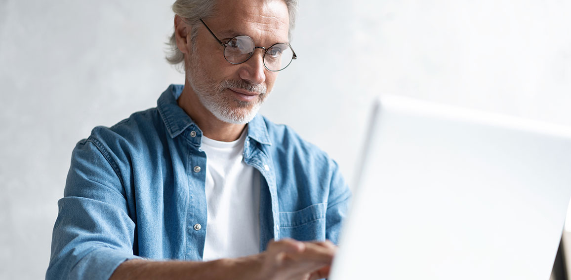 Middle-aged man working from home-office on laptop.