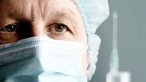Mature male surgeon with syringe is preparing for injection