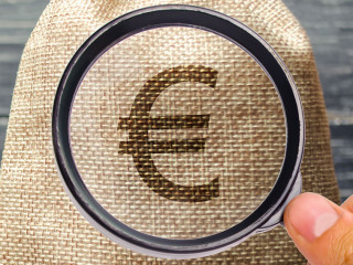 A money bag and a wooden house on the scales. The concept of real estate purchase. Sale of property. Payment of the mortgage. Redemption of taxes. Tax refund. Legacy / Inheritance tax concept