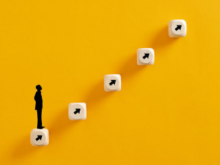 Businessperson icon standing on wooden cubes ladder wit arrows p