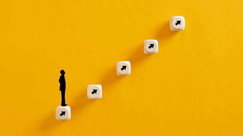 Businessperson icon standing on wooden cubes ladder wit arrows p