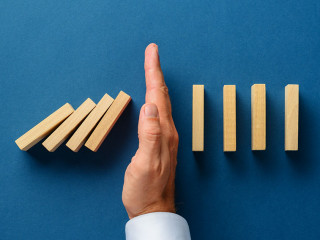 View from above of male hand interfering collapsing dominos