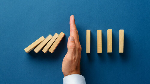 View from above of male hand interfering collapsing dominos