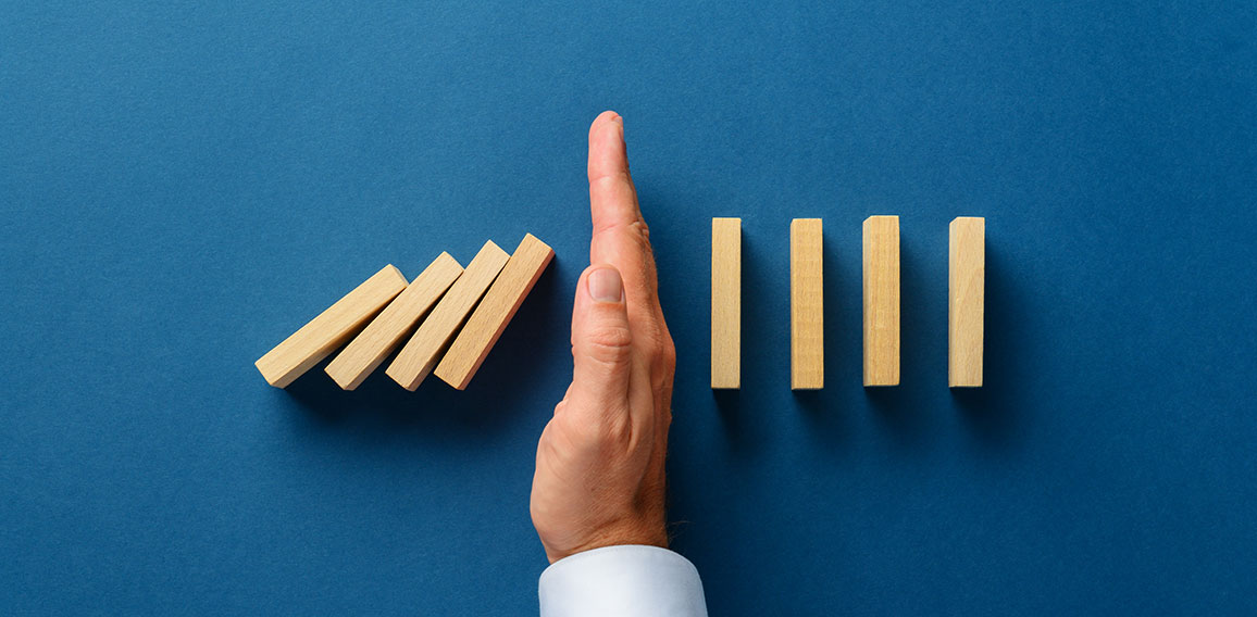 View from above of male hand interfering collapsing dominos