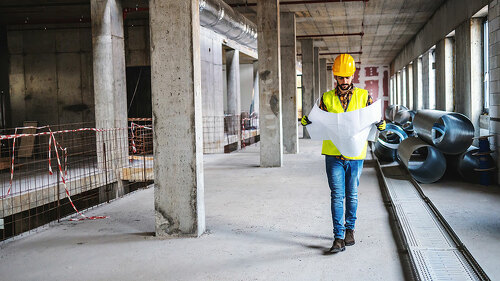 Full length of construction worker in work wear walking in build