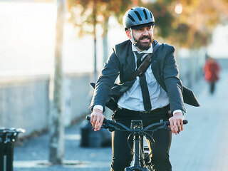 Hipster businessman commuter with electric bicycle traveling home from work in city.