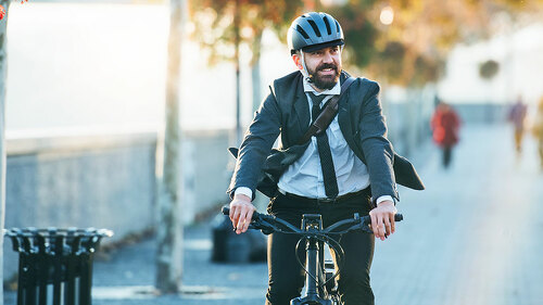 Hipster businessman commuter with electric bicycle traveling home from work in city.