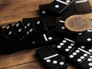 Shiny one euro coin lying on top of spilled domino tiles.